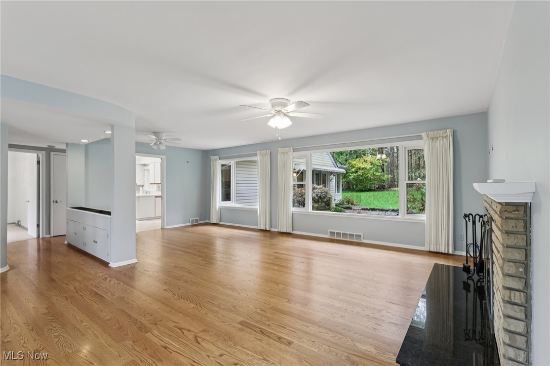 33300 South Woodland Road Cleveland, OH 44124 - Photo 12 of 50 Unfurnished living room with light wood-style flooring, a fireplace, a barn door, and ceiling fan