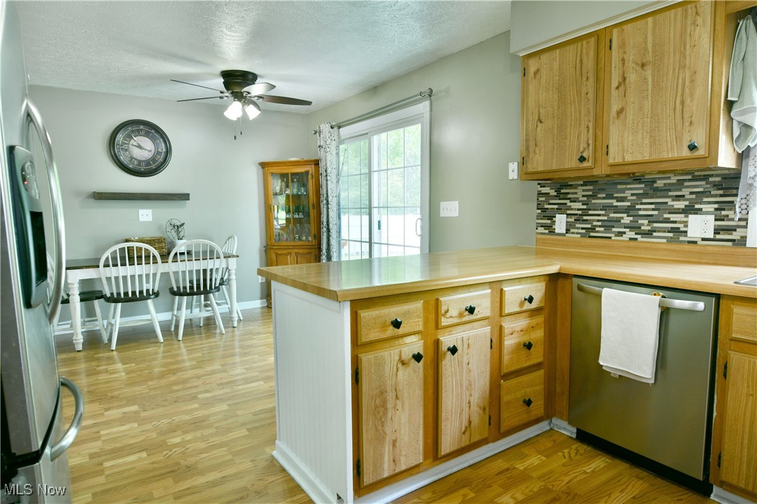 2847 Selkirk Bush Road Warren, OH 44481 - Photo 10 of 47 Kitchen featuring stainless steel appliances, a ceiling fan, a peninsula, backsplash, and light wood-style floors