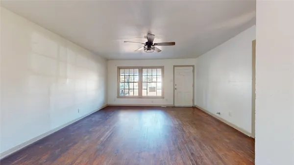 an empty room with wooden floor ceiling fan and windows