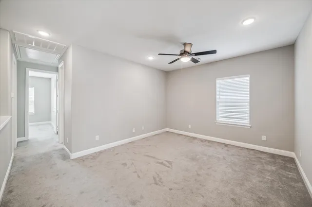 an empty room with ceiling fan and window