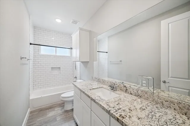 a bathroom with a granite countertop sink a toilet a mirror and shower