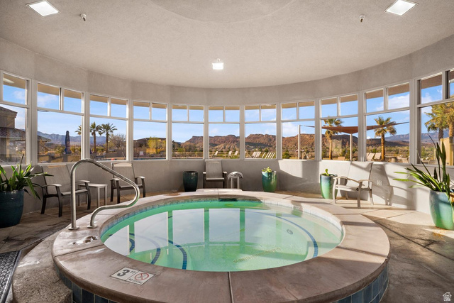 1587 Whitestone Drive St. George, UT 84790 - Photo 34 of 36 Circular indoor spa with a stone surround and integrated handrails, set within a curved room featuring a panoramic wall of windows