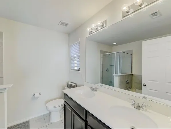 a bathroom with a sink a toilet a mirror and shower