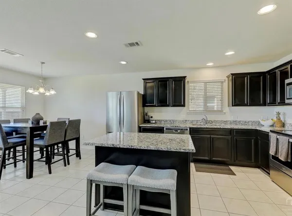 a large kitchen with granite countertop a stove a sink a dining table and chairs