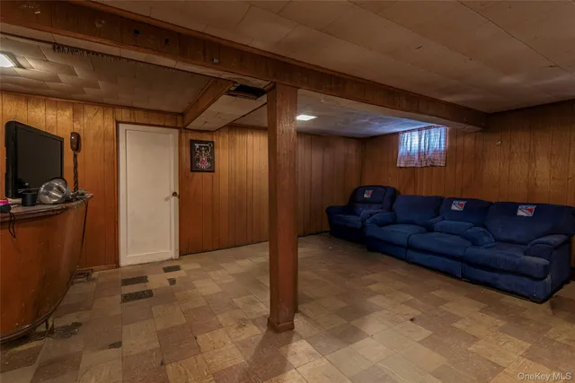 a living room with furniture a flat screen tv and a refrigerator