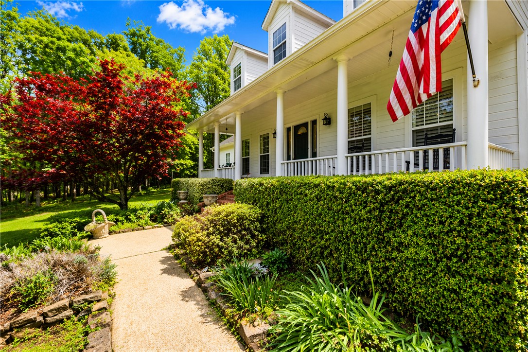 14203 Greenridge Road Fayetteville, AR 72701 - Photo 2 of 25 White siding residence with a covered front porch featuring white columns and railing. This image is altered by AI to show green grass.