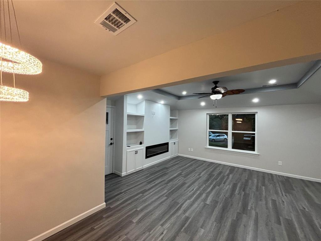 8455 Sugarberry Road Dallas, TX 75249 - Photo 12 of 18 an empty room with wooden floor fireplace and windows