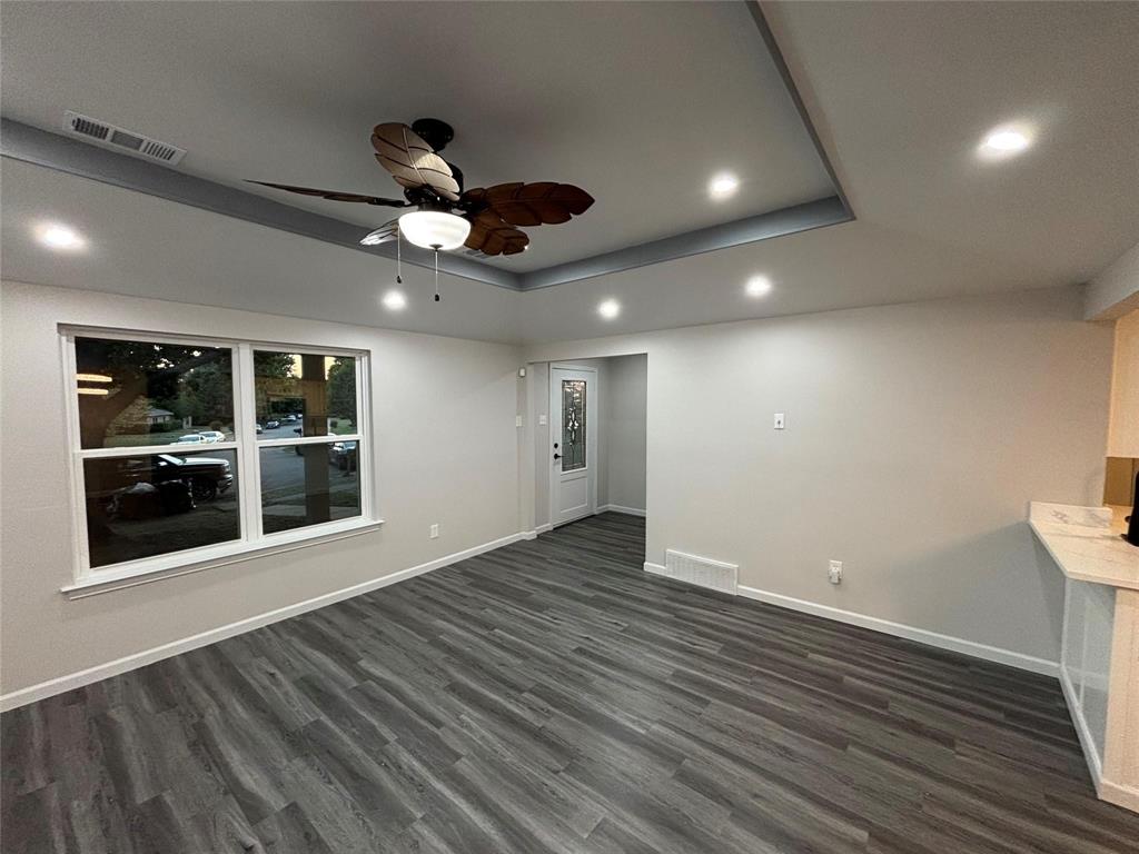 8455 Sugarberry Road Dallas, TX 75249 - Photo 3 of 18 a view of an empty room with wooden floor and a window