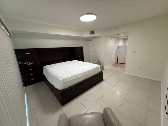 a room with a bed and a potted plant on dresser