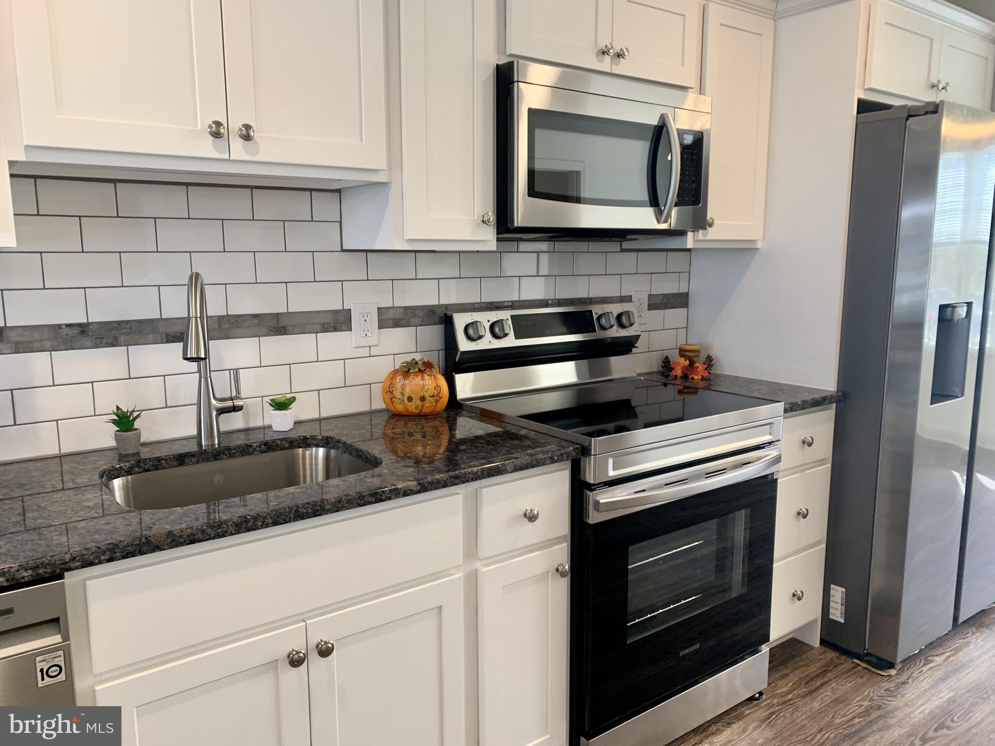 46 West Pittsfield Street Pennsville, NJ 08070 - Photo 5 of 25 a kitchen with granite countertop a stove microwave and sink