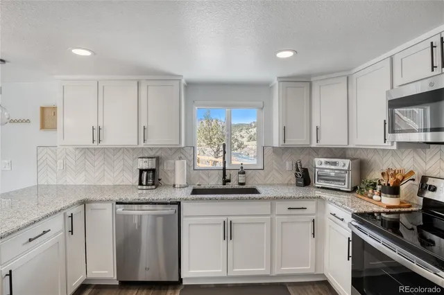 a kitchen with stainless steel appliances granite countertop white cabinets sink and window