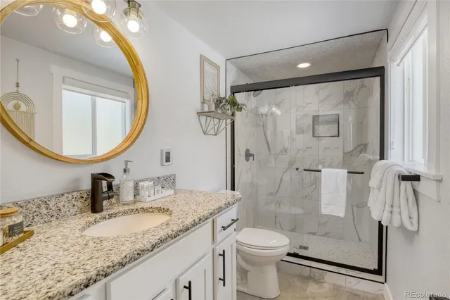 a bathroom with a granite countertop sink a toilet and a mirror