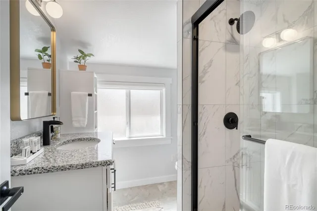 a bathroom with a granite countertop sink a mirror and shower