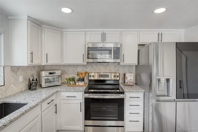a kitchen with refrigerator a microwave a sink and cabinets