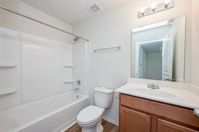 a bathroom with a toilet a sink a mirror a bathtub and vanity