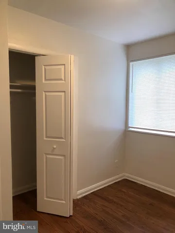an empty room with wooden floor closet and windows