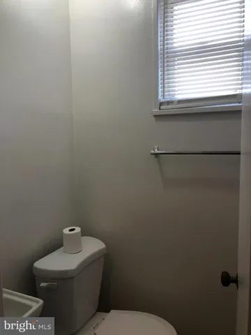 a white toilet sitting next to a window in a bathroom