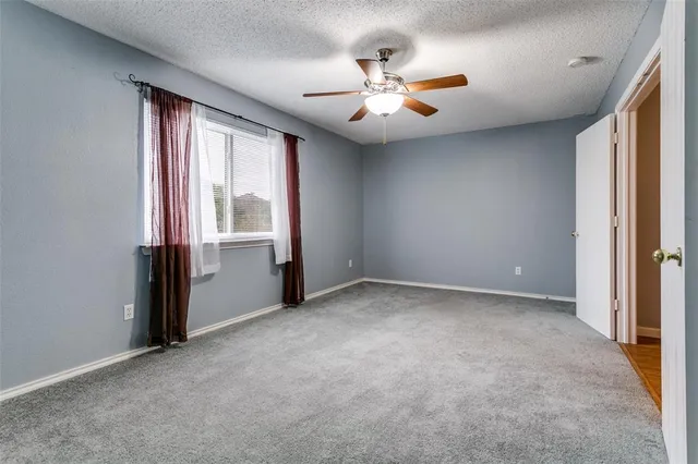 an empty room with windows and chandelier fan