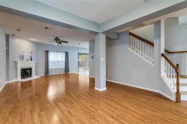 a view of an empty room with fireplace and wooden floor