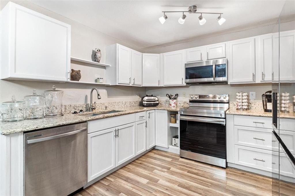 398 Rose Street Umatilla, FL 32784 - Photo 11 of 30 a kitchen with granite countertop a sink stainless steel appliances and white cabinets