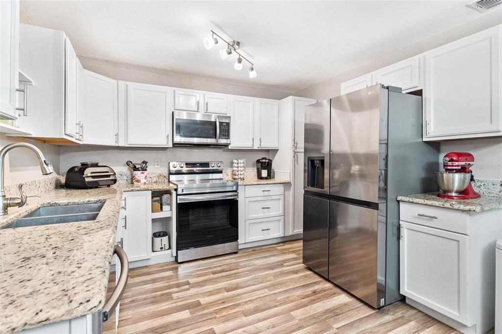 398 Rose Street Umatilla, FL 32784 - Photo 9 of 30 a kitchen with granite countertop a refrigerator stove and sink