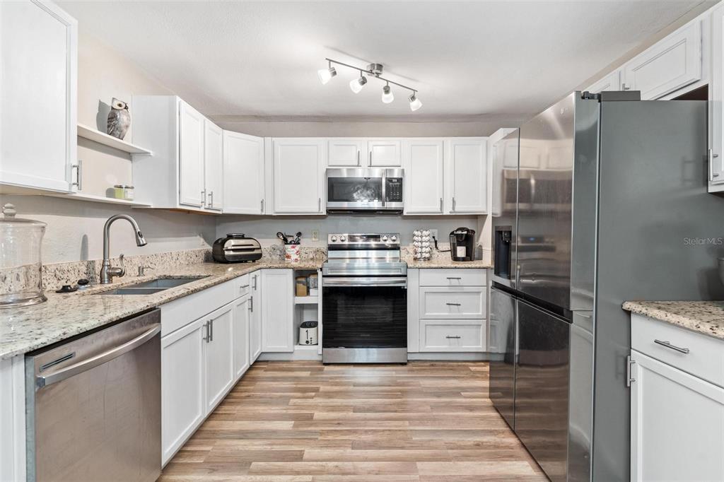 398 Rose Street Umatilla, FL 32784 - Photo 10 of 30 a kitchen with stainless steel appliances granite countertop a stove top oven a sink and a refrigerator