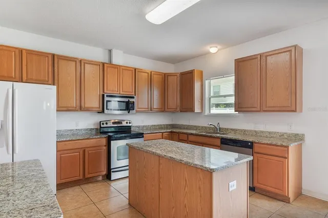 a kitchen with a stove a kitchen island a sink and a refrigerator