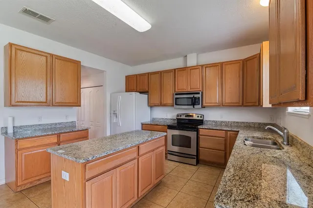 a kitchen with granite countertop a sink stainless steel appliances white cabinets and a window