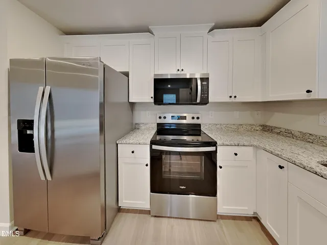 a kitchen with stainless steel appliances a stove a refrigerator and white cabinets