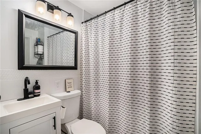 a bathroom with a toilet a sink a mirror and shower curtain