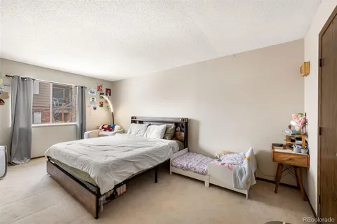 a bedroom with a bed table chair and a window