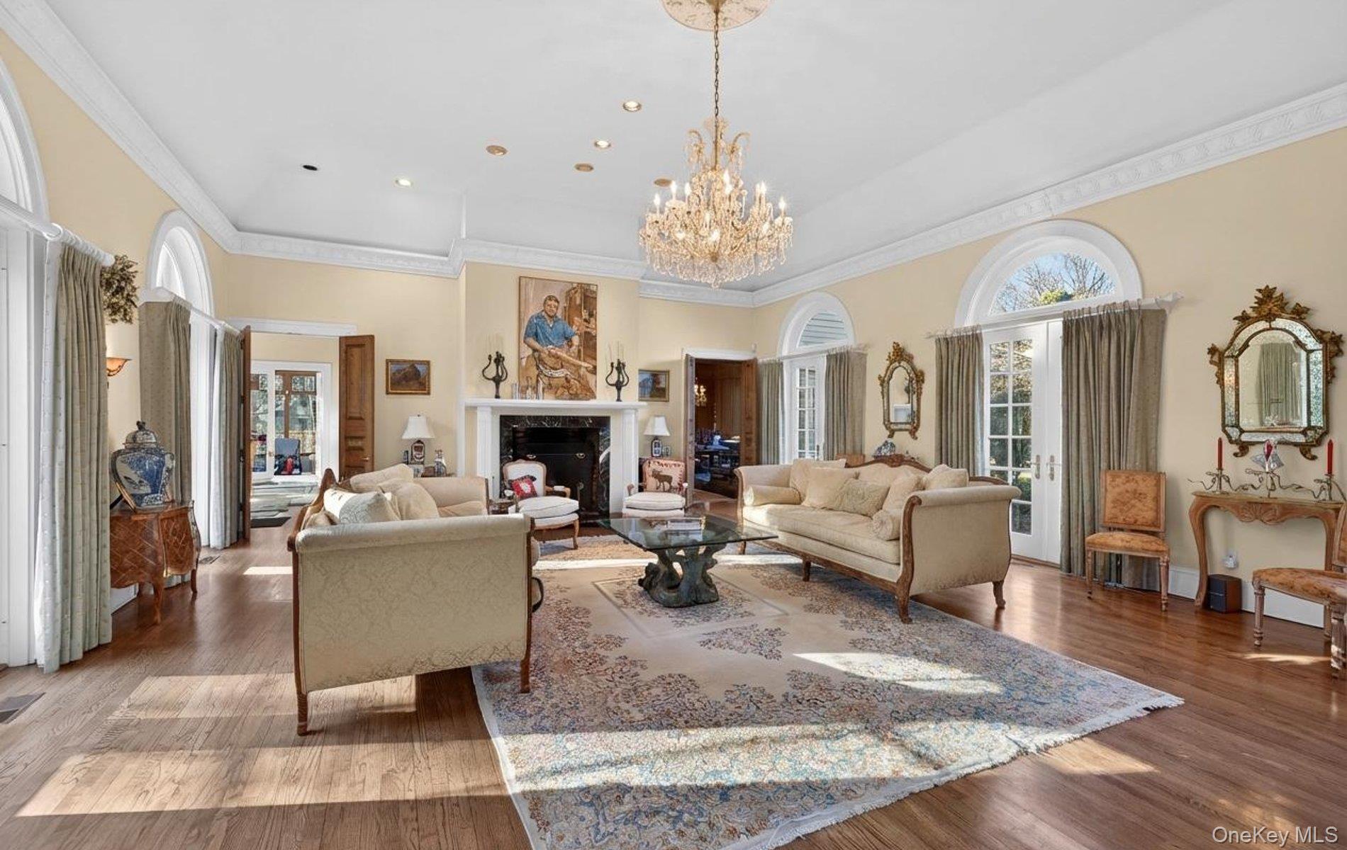 38 Tiffany Road Oyster Bay, NY 11771 - Photo 13 of 50 Living area with wood finished floors, suspended lighting, crown molding, a fireplace, 14 ft high ceiling