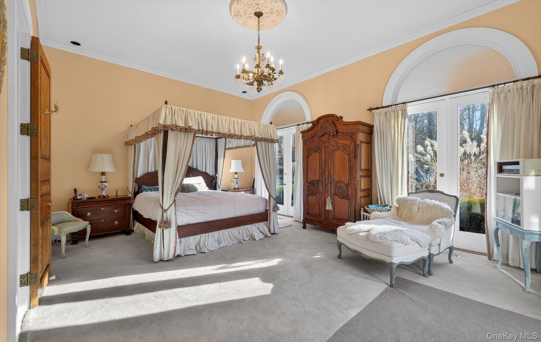 38 Tiffany Road Oyster Bay, NY 11771 - Photo 16 of 50 Primary Bedroom with 14 feet ceilings, carpet flooring, crown molding, hanging lights, and 3 French doors