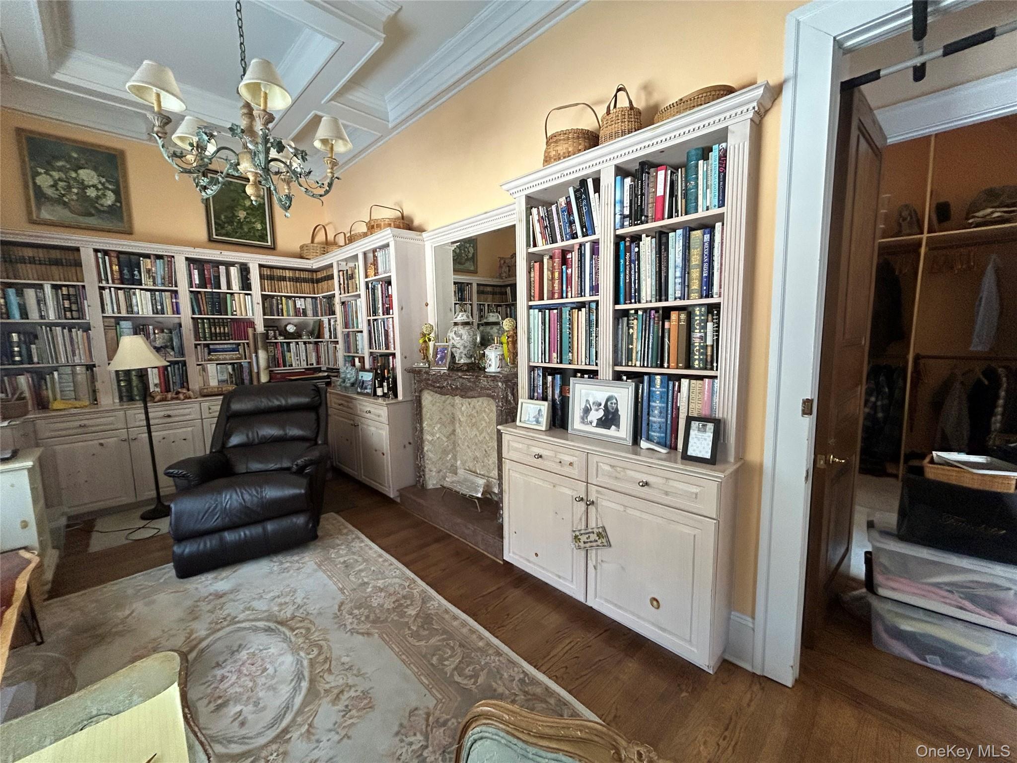 38 Tiffany Road Oyster Bay, NY 11771 - Photo 18 of 50 Bedroom-Sitting room featuring custom coffered ceiling, dark wood-style flooring, crown molding, bookshelves, and a custom marble tiled faux fireplace