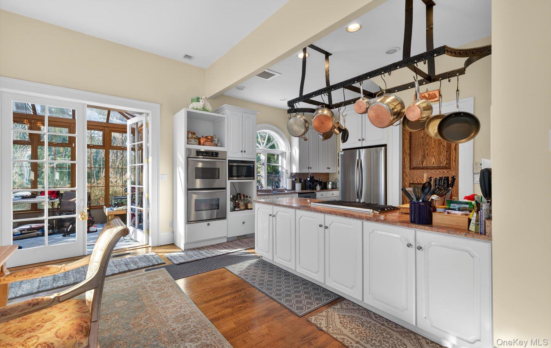 38 Tiffany Road Oyster Bay, NY 11771 - Photo 23 of 50 French country style Kitchen featuring white cabinetry, stainless steel appliances, open shelves, light stone counters, and recessed lighting, wood floors- Rumford fireplace