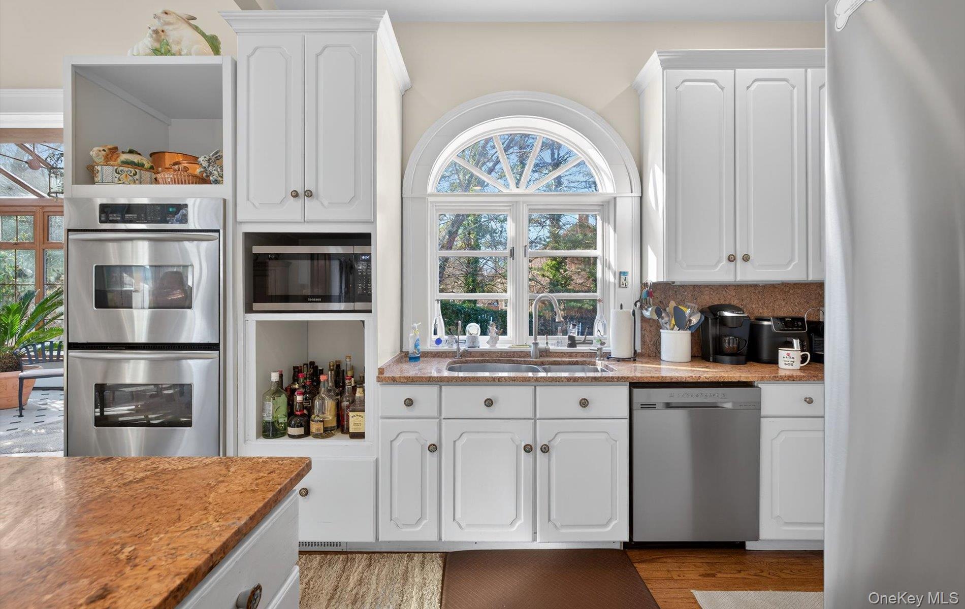 38 Tiffany Road Oyster Bay, NY 11771 - Photo 25 of 50 Kitchen with light stone counters, stainless steel appliances, white cabinets, backsplash, and light wood-style flooring