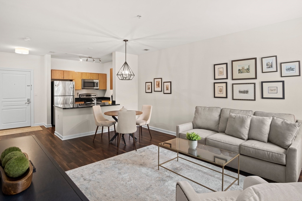 a living room with furniture kitchen view and a wooden floor