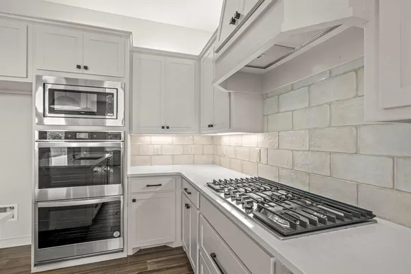 a kitchen with white cabinets and stainless steel appliances