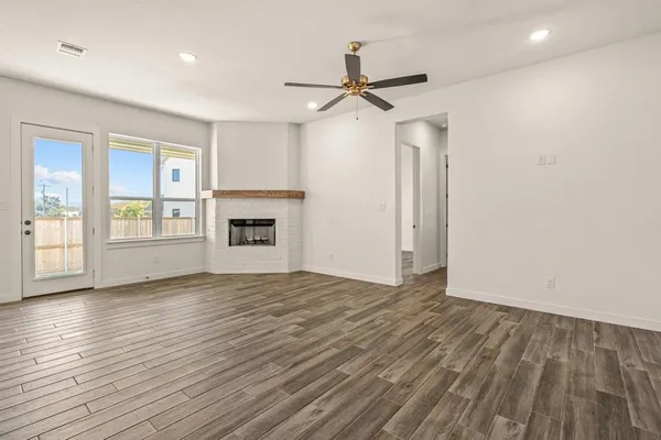 a view of an empty room with a window and a kitchen