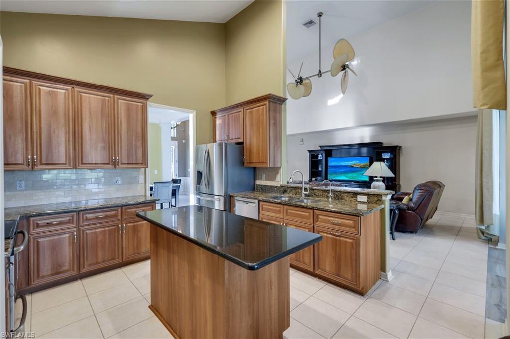 17896 Modena Road Miromar Lakes, FL 33913 - Photo 13 of 38 Eat in Kitchen featuring appliances with stainless steel finishes, a center island, high vaulted ceiling, and dark stone counters overlooking grand room.