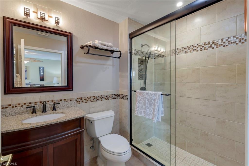 17896 Modena Road Miromar Lakes, FL 33913 - Photo 16 of 38 Updated BR2 Ensuite Bathroom with an enclosed shower, elevated vanity, toilet, and tile walls