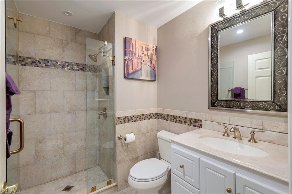 17896 Modena Road Miromar Lakes, FL 33913 - Photo 18 of 38 Updated BR#3 Ensuite Bathroom with vanity, toilet, an enclosed shower, and tile walls