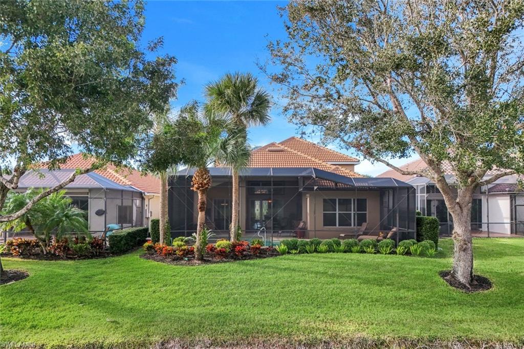 17896 Modena Road Miromar Lakes, FL 33913 - Photo 32 of 38 Rear view of house featuring a yard and glass enclosure