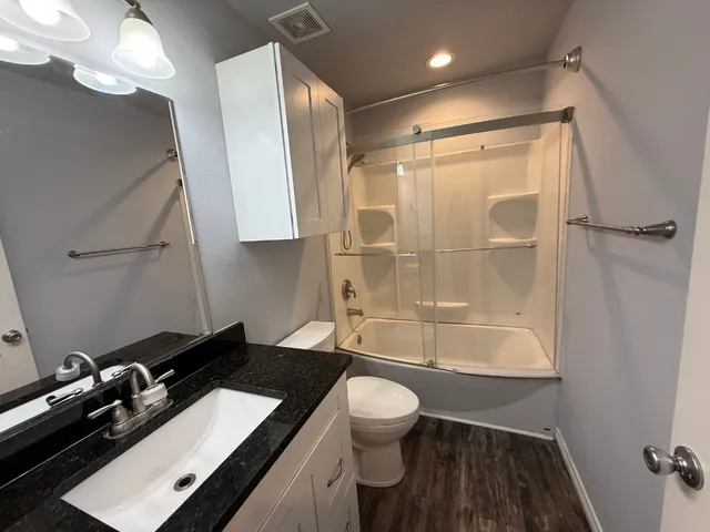 a bathroom with a sink a toilet a mirror and shower