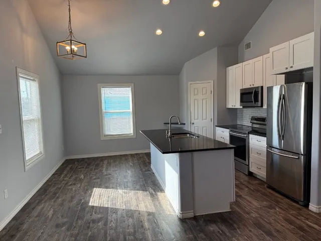 a kitchen with kitchen island granite countertop a sink and a refrigerator