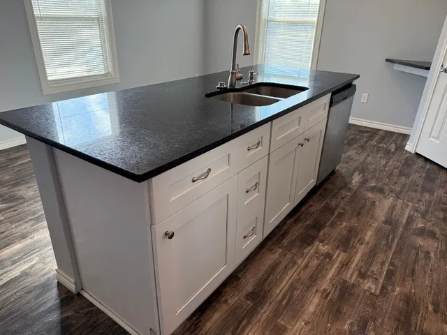 a kitchen with granite countertop a sink and cabinets