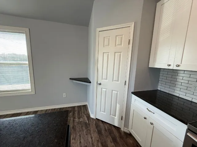 a kitchen with granite countertop white cabinets and black appliances