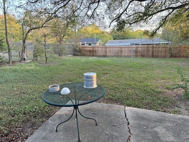 a view of a backyard with table and chairs and wooden fence