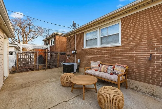 a view of a patio with couches table and chairs and wooden fence