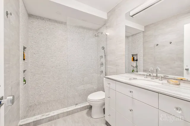 a bathroom with a granite countertop sink toilet a large mirror a shower and a bathtub